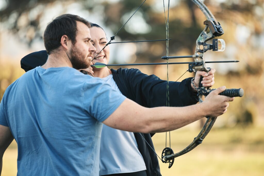 Archery, bow and shooting range sports training with a woman and man outdoor for target practice. A